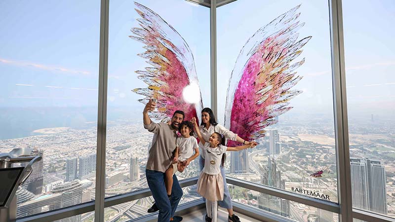 Family taking a picture with a view of the city on a high floor of a building